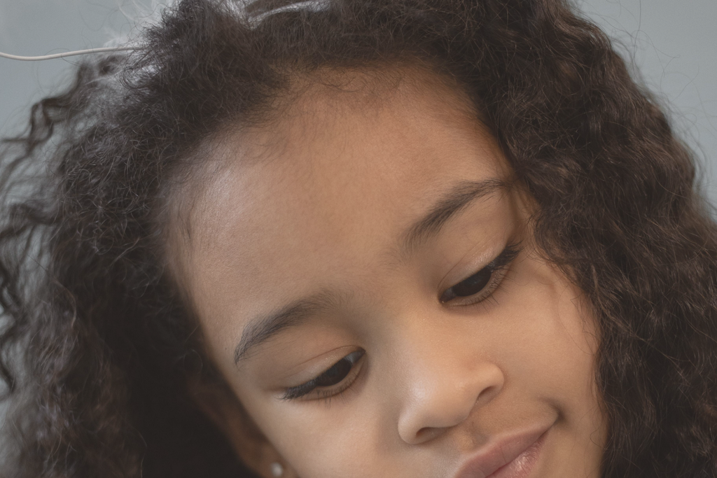 Bambina con capelli ricci lunghi e allungati lasciati sciolti