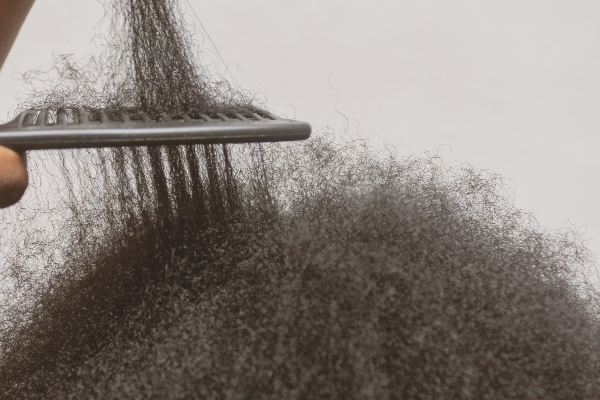 Primo piano di capelli afro durante il districamento con un pettine