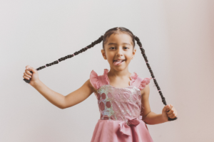 Bambina sorridente con lunghi capelli intrecciati in due trecce